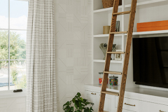Guest bedroom has a wall of white custom built-ins with an integrated ladder.